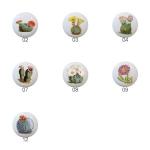 May include: A collection of twelve white ceramic cabinet knobs, each featuring a different watercolor illustration of cacti and succulents with various flower colors. The knobs are numbered 01 through 12.