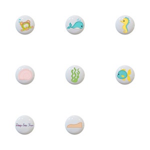 May include: Set of 13 ceramic knobs featuring various sea creatures and ocean-themed designs. The knobs are white with colorful illustrations of a seahorse, whale, starfish, fish, seashells, seaweed, and a submarine. One knob features the text "Deep Sea Fun".