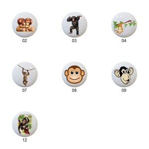 May include: Twelve ceramic knobs with different monkey designs. The knobs are white with brown, black, and yellow accents. The monkeys are depicted in various poses, including sitting, swinging, and holding bananas.