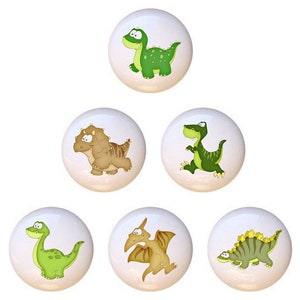 May include: Set of six ceramic knobs featuring cartoon dinosaurs in various colors, including green, brown, and yellow. The dinosaurs are depicted in a playful and whimsical style.