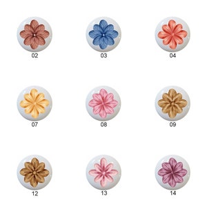 May include: Fifteen round ceramic knobs with a flower design in various colors, including pink, blue, yellow, and brown. Each knob is numbered 01 through 15.