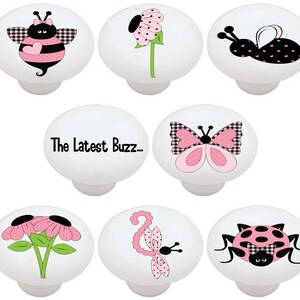 May include: Set of 7 ceramic knobs featuring a pink and black bee, butterfly, ladybug, dragonfly, flower, and text that reads "The Latest Buzz..."
