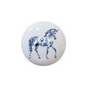 May include: A white, round decorative object featuring a blue and white floral horse design. The horse is depicted in a classical style, with intricate floral patterns adorning its body. The object has a glossy finish.