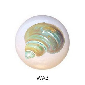 May include: Five white ceramic knobs with different sea-themed designs. The knobs feature a seashell, a sand dollar, a conch shell, a starfish, and a cone shell.