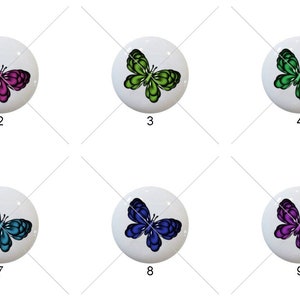 May include: Nine white ceramic round buttons with butterfly designs. The butterflies are in various colors, including red, pink, green, blue, and purple.