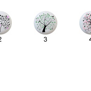 May include: Six different designs of ceramic knobs featuring a stylized tree with various colored leaves. The knobs are round and white with black outlines.