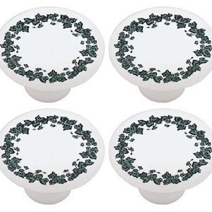 May include: Set of four white ceramic knobs with a green ivy design. Each knob has a circular design with a green ivy wreath around the edge.