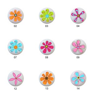 May include: Fifteen different floral designs on white ceramic knobs. Each knob features a different colorful flower with a variety of patterns and colors.