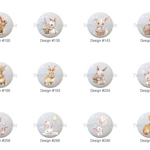 May include: A collection of decorative cabinet knobs featuring watercolor illustrations of bunnies. Each knob has a light gray background and a unique bunny design, with text labels like "Design #100" and "Design #135".
