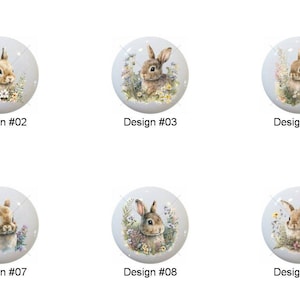 May include: A collection of ten white ceramic cabinet knobs, each featuring a different watercolor illustration of a bunny surrounded by flowers. Each knob is labeled with a design number from #01 to #10.