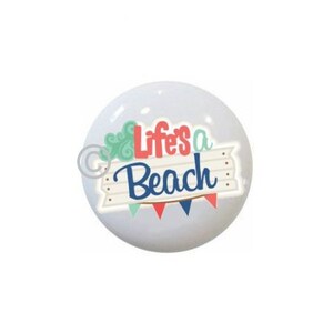 May include: White ceramic round ornament with a blue and red design that says "Life's a Beach" with a green and white cloud design.