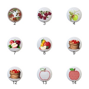 May include: Set of 14 ceramic knobs featuring various apple designs. The knobs are white with red, green, and brown accents. Some designs include apples in a basket, apples on a branch, and a single apple.
