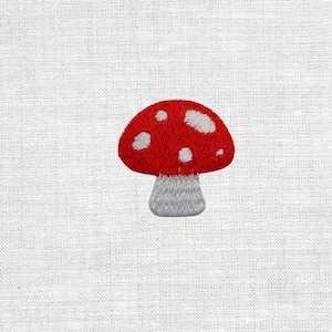 Könnte beinhalten: Gestickter Aufnäher mit einem roten Pilz mit weißen Punkten und einem grauen Stiel. Das Pilzdesign befindet sich auf einem weißen Stoffhintergrund. Dieser Aufnäher eignet sich für Kleidung, Taschen oder andere Stoffartikel.