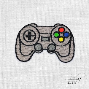 Könnte beinhalten: Gestickter grauer Videospiel-Controller-Patch mit schwarzer Umrandung. Der Controller verfügt über ein Steuerkreuz, Knöpfe in Rot, Grün, Blau und Gelb sowie zwei graue Knöpfe. Der Patch befindet sich auf einem weißen Stoffhintergrund.