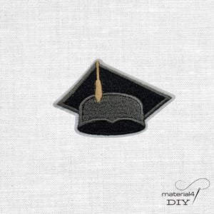 Könnte beinhalten: Gestickter Abschlusskappen-Aufnäher in Schwarz, Grau und Gold. Der Mortarboard ist schwarz mit einem grauen Rand, und die Quaste ist goldfarben. Die Basis der Kappe ist grau. Der Aufnäher befindet sich auf einem weißen Stoffhintergrund.