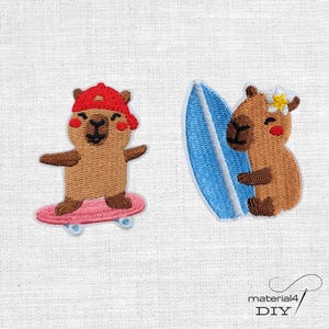 Könnte beinhalten: Zwei gestickte Aufnäher mit braunen Wasserschweinen. Der linke Aufnäher zeigt ein Wasserschwein mit roter Baseballkappe auf einem rosa Skateboard. Der rechte Aufnäher zeigt ein Wasserschwein mit einer weißen Blume am Ohr neben einem blauen Surfbrett.