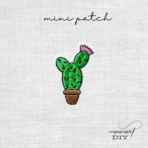 Könnte beinhalten: Ein gestickter Mini-Aufnäher, der einen grünen Kaktus mit einer rosa Blüte in einem braunen Topf zeigt. Der Text mini patch steht über dem Kaktus und der Text material4 DIY befindet sich in der unteren rechten Ecke auf weißem Stoff.