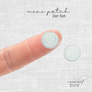 Könnte beinhalten: Zwei kleine, kreisförmige, hellblaue gestickte Aufnäher mit einem strukturierten Gittermuster. Der Text "mini patch 2er Set" ist oben sichtbar, und der Text "material4 DIY" ist unten rechts im Bild zu sehen.