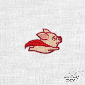 Könnte beinhalten: Ein gestickter Aufnäher, der ein hellbeiges Ferkel mit einem leuchtend roten Umhang zeigt. Das Ferkel ist in einer fliegenden Pose dargestellt, mit nach oben gerichteten Ohren und einem kleinen Rüssel. Die Stickerei nutzt detaillierte Stiche.