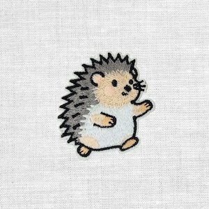 Könnte beinhalten: Gestickter Aufnäher mit einem Cartoon-Igel mit hellbraunem Gesicht, grauen Stacheln und einem weißen Bauch. Der Igel läuft mit erhobenem Arm. Der Aufnäher ist schwarz umrandet und befindet sich auf weißem Stoff.