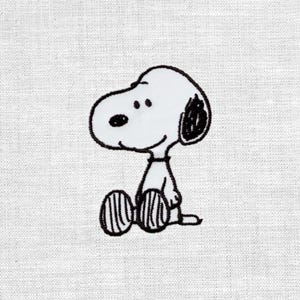 Könnte beinhalten: Eine schwarz-weiße Stickerei mit Snoopy, der Zeichentrickfigur, die sitzt. Das Bild ist vor einem weißen Stoffhintergrund platziert, der die detaillierten Stiche des Designs hervorhebt.
