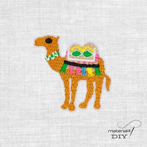 Könnte beinhalten: Gestickter Aufnäher eines Kamels in Braun-, Orange- und Beigetönen mit farbenfrohen Satteldetails. Das Kamel hat einen grün-weißen Kragen. Der Aufnäher befindet sich auf weißem Hintergrund. Der Text "material4 DIY" befindet sich unten rechts.