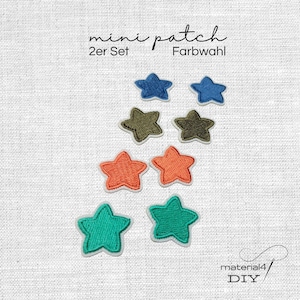 Könnte beinhalten: Ein Set aus acht bestickten sternförmigen Aufnähern in vier verschiedenen Farben, darunter Blau, Olivgrün, Orange und Türkis. Der Text "mini patch 2er Set Farbwahl" und "material4 DIY" ist auf dem weißen, strukturierten Stoffhintergrund zu sehen.