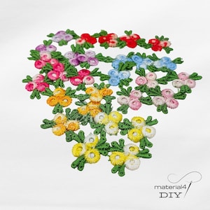 Könnte beinhalten: Eine Sammlung bunter, gestickter Blumenapplikationen in verschiedenen Farben, darunter Rot, Rosa, Blau, Gelb und Lila. Jede Blume ist an einem grünen Stiel mit Blättern befestigt. Die Applikationen sind auf weißem Hintergrund angeordnet.