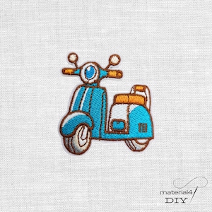 Könnte beinhalten: Gestickter Aufnäher mit einem blau-braunen Roller-Design. Der Roller hat einen hellblauen Körper mit braunen Akzenten an Lenker, Rädern und Sitz. Der Aufnäher befindet sich auf einem weißen Stoffhintergrund.