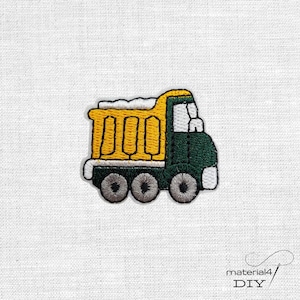 Könnte beinhalten: Gestickter Aufnäher eines gelb-grünen Muldenkippers mit drei grauen Rädern. Der LKW hat eine weiße Umrandung und einen weißen Abschnitt oben. Der Aufnäher befindet sich auf einem weißen Stoffhintergrund.