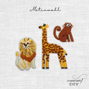 Könnte beinhalten: Drei gestickte Stoffaufnäher mit einem Löwen mit goldener Mähne, einer großen Giraffe mit braunen Flecken und einem braunen Affen mit geringeltem Schwanz. Der Text "Motivwahl" steht oben und "material4 DIY" unten rechts.