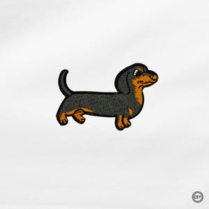 Könnte beinhalten: Gestickter Aufnäher mit einem Cartoon-Dackel. Der Hund hat einen schwarzen Körper mit orangefarbenen und braunen Akzenten. Der Aufnäher ist zum Aufbügeln oder Aufnähen auf Stoff gedacht. Der Aufnäher befindet sich auf weißem Hintergrund.