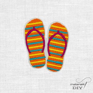 Könnte beinhalten: Gesticktes Paar Flip-Flops mit orange, gelben und blauen horizontalen Streifen. Die Riemen sind magenta. Die Flip-Flops befinden sich auf weißem Hintergrund. Das Bild ist ein DIY-Bastelprojekt.