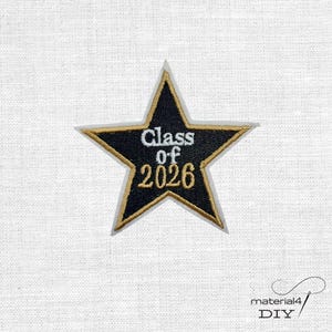Könnte beinhalten: Gestickter sternförmiger Aufnäher mit schwarzem Zentrum und goldenem Rand. Der Aufnäher trägt den Text "Class of 2026" in Weiß und Gold, geeignet für Abschlusskleidung oder Feiern.