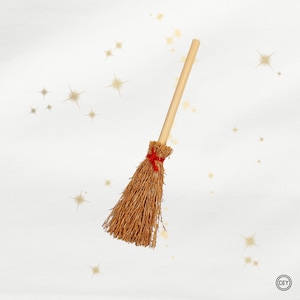 Könnte beinhalten: Ein kleiner, dekorativer Besen mit einem hellbraunen Strohkopf und einem Holzgriff. Das Stroh ist mit einem roten Band gebunden. Der Hintergrund ist weiß mit goldenen Sternakzenten. Ein DIY-Logo befindet sich in der unteren rechten Ecke.