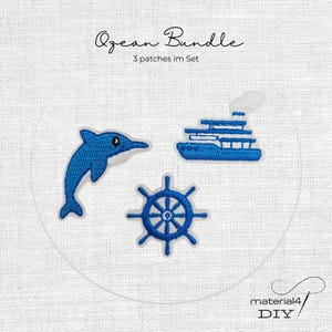 Könnte beinhalten: Ein Set aus drei bestickten Aufnähern mit einem blauen Delfin, einem blauen Schiff und einem blauen Schiffssteuerrad. Der Text "Ozean Bundle" und "3 patches im Set" steht darüber, und "material4 DIY" steht unter den Aufnähern.