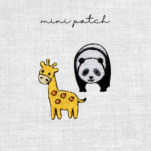 Könnte beinhalten: Gestickte Aufnäher mit einer gelben Giraffe mit orangefarbenen Flecken und einem schwarz-weißen Pandabären. Der Text "mini patch" steht in Schreibschrift über den Aufnähern. Die Aufnäher befinden sich auf einem weißen Stoffhintergrund.