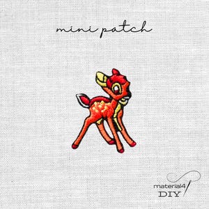 Könnte beinhalten: Gestickter Mini-Patch mit einem Cartoon-Hirsch in Orange, Rot und Gelb. Der Patch trägt den Text "mini patch" in Schreibschrift über dem Hirsch. Der Patch befindet sich auf einem weißen Stoffhintergrund. Der Text "material4 DIY" befindet sich unten rechts.