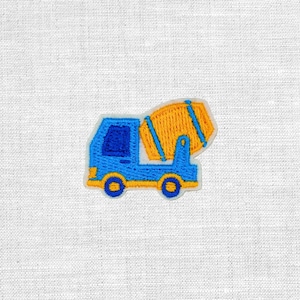 Könnte beinhalten: Ein gestickter Aufnäher in Form eines Betonmischers. Der LKW-Aufbau ist leuchtend blau mit einem gelben Kabinenfenster und einer großen, strukturierten gelben Mischtrommel mit blauen Akzenten. Die Räder sind gelb mit blauen Radmitten gestaltet.