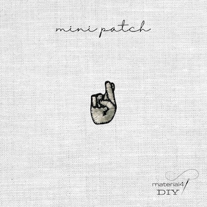 Könnte beinhalten: Ein kleiner gestickter Aufnäher, der eine Hand mit gekreuzten Fingern in schwarzem und weißem Garn zeigt. Der Text 'mini patch' steht über dem Motiv und der Text 'material4 DIY' befindet sich in der unteren rechten Ecke des Bildes.
