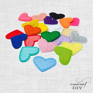 Könnte beinhalten: Eine Sammlung von herzförmigen gestickten Aufnähern in verschiedenen Farben wie Rot, Blau, Gelb, Grün, Orange, Pink, Lila, Schwarz, Weiß und Silber. Jeder Aufnäher hat eine dichte Fadenstruktur und einen festen Rand. Text: material4 DIY.