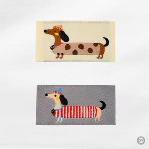 Könnte beinhalten: Zwei bestickte Dackel-Patches. Einer zeigt einen braunen Hund mit geflecktem Körper und Hut, der andere hat einen rot-weiß gestreiften Körper und einen blauen Hut. Beide befinden sich auf rechteckigen Hintergründen.