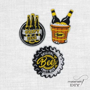 Könnte beinhalten: Drei bestickte Aufnäher mit Biermotiven. Ein runder Aufnäher zeigt drei Bierflaschen mit dem Text CRAFT BEER. Ein weiterer zeigt zwei Flaschen in einem Holzeimer mit der Aufschrift BEER. Der dritte ist ein Kronkorken mit dem Text ORIGINAL BEER.