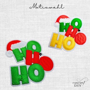 Könnte beinhalten: Zwei gestickte Aufnäher mit dem Schriftzug Ho Ho Ho in grünen, roten und gelben Garnfarben. Die Buchstaben sind mit einer rot-weißen Weihnachtsmannmütze und einer roten Weihnachtskugel verziert. Der Text Motivwahl ist oben zu sehen.
