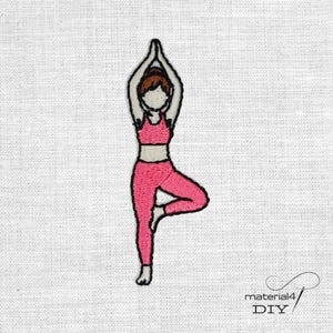 Könnte beinhalten: Ein gestickter Aufnäher, der eine Figur in der Yoga-Baum-Pose zeigt. Die Figur hat braune Haare und trägt ein leuchtend pinkfarbenes, zweiteiliges Sportoutfit bestehend aus einem bauchfreien Oberteil und einer Leggings mit schwarzen Konturen.