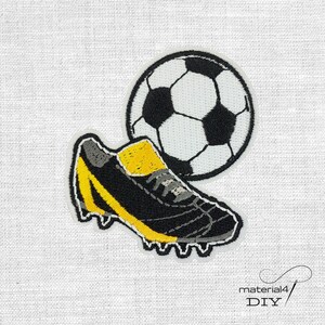 Könnte beinhalten: Gestickter Aufnäher mit einem Fußball und einem Fußballschuh. Der Fußball ist schwarz und weiß, und der Schuh ist schwarz und gelb. Der Aufnäher befindet sich auf weißem Hintergrund. Der Text "material4 DIY" befindet sich unten rechts.