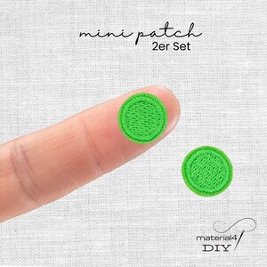 Könnte beinhalten: Ein Set aus zwei kleinen, runden, hellgrünen Stickaufnähern. Der Text "mini patch 2er Set" ist oben zu sehen, und der Text "material4 DIY" ist unten rechts zu sehen. Die Aufnäher weisen ein dichtes, strukturiertes Stickmuster auf.