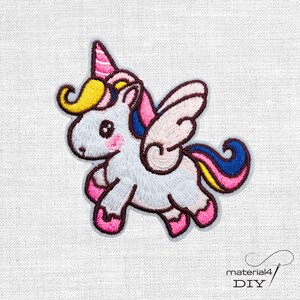 Könnte beinhalten: Ein gestickter Aufbügler in Form eines weißen Einhorns mit gelber Mähne, rosa Horn und hellrosa Flügeln. Das Einhorn hat einen mehrfarbigen Schweif mit blauen, rosa und gelben Abschnitten sowie rosa Hufe, alles mit dunkelbraunem Garn umrandet.