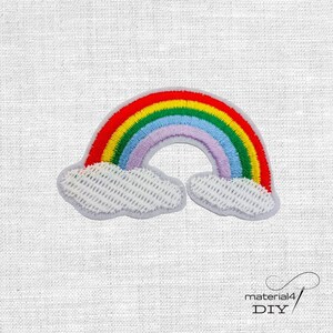 Könnte beinhalten: Gestickter Regenbogen-Aufnäher mit roten, orangen, gelben, grünen, blauen und violetten Bögen. Der Regenbogen befindet sich über zwei weißen Wolken. Der Aufnäher befindet sich auf einem weißen Stoffhintergrund. Der Text "material4 DIY" befindet sich unten rechts.