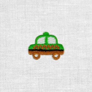 Könnte beinhalten: Ein gestickter Aufnäher in Form eines Autos mit hellgrünem Oberteil und weißen Fenstern, einem orange-weiß karierten Mittelstreifen sowie einem braunen Unterteil mit zwei runden braunen Rädern mit weißem Mittelpunkt.